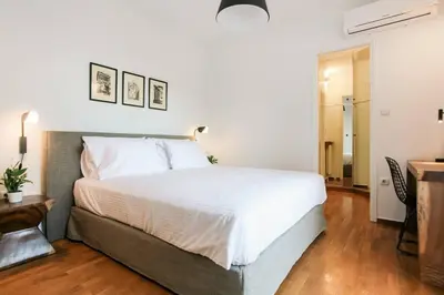 a bedroom with a large white bed and a table at Acropolis Veranda Residence in Athens