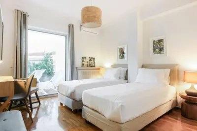 a bedroom with two beds and a desk and a window at Acropolis Veranda Residence in Athens