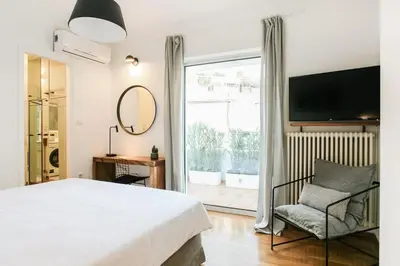 a bedroom with a bed and a chair and a large window at Acropolis Veranda Residence in Athens