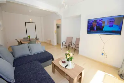 a living room with a couch and a tv on a wall at Eclectic Apartment with Stunning Seaview in Porto Rafti
