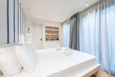 a white bedroom with a large bed with white pillows at The Asprogeraka - self check-in rooms in Athens