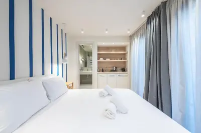 a white bedroom with two white beds and curtains at The Asprogeraka - self check-in rooms in Athens