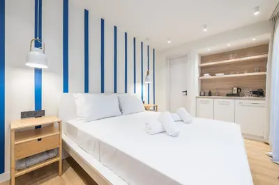 a bedroom with a large white bed with blue and white stripes at The Asprogeraka - self check-in rooms in Athens