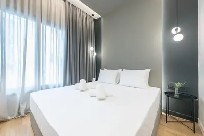 a white bed in a room with a large window at The Asprogeraka - self check-in rooms in Athens