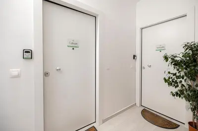 two white doors in a hallway with plants at Calliope Apartment in Athens