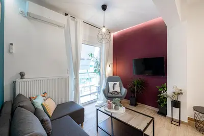 a living room with a gray couch and a red wall at Calliope Apartment in Athens