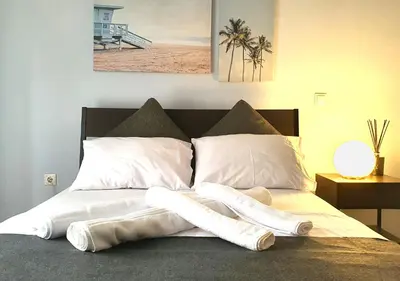 a bed with white sheets and pillows on it at Pame Rentals - Entire Apartment with Free Parking in Athens