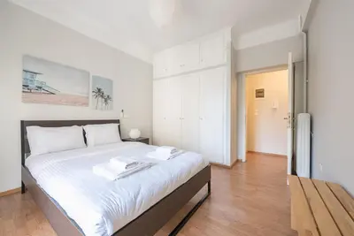 a white bedroom with a large bed with white sheets at Pame Rentals - Entire Apartment with Free Parking in Athens