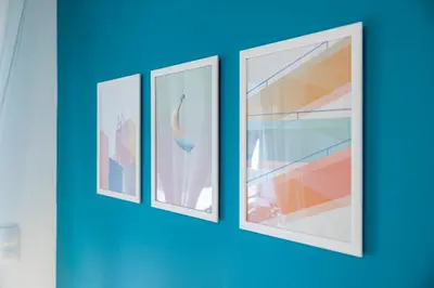 four framed pictures on a blue wall at Aphrodite Apartment in Athens