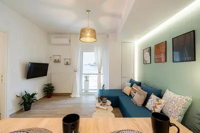 a living room with a blue couch and a tv at Hestia Apartment in Athens