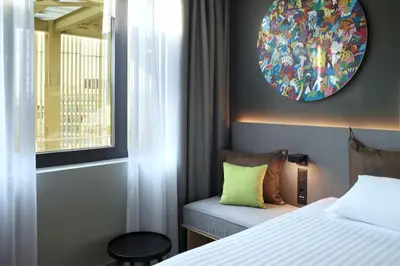 a bedroom with a bed and a mirror and a window at Moxy Athens City in Athens