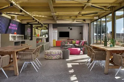 a patio with tables and chairs and a living room at Moxy Athens City in Athens