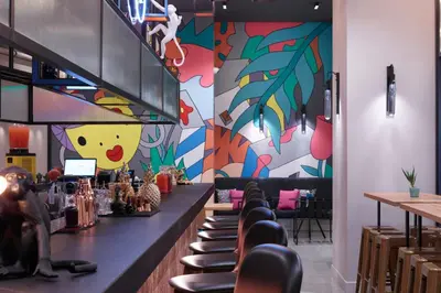 a restaurant with a bar with a colorful wall at Moxy Athens City in Athens