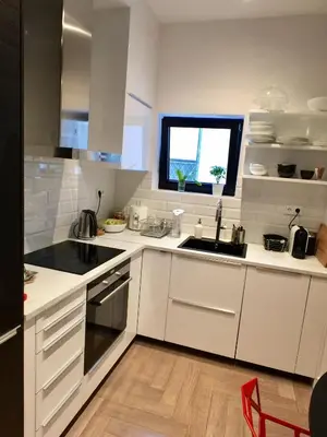 a kitchen with white cabinets and a sink and a window at Vibrant Urban Chic Apartment in Athens