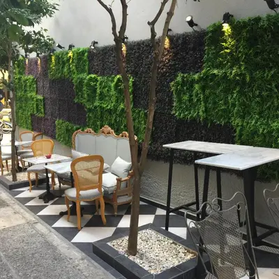 a patio with tables and chairs and a hedge at Vibrant Urban Chic Apartment in Athens