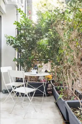 a table and chairs on a balcony with trees at Vibrant Urban Chic Apartment in Athens