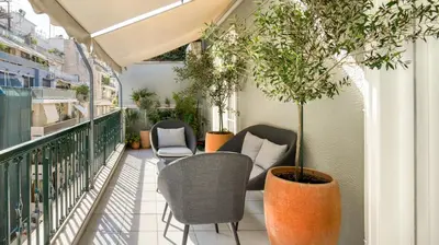 a balcony with chairs and potted plants on it at Alopekis in Athens