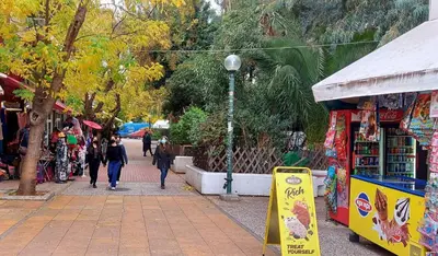 a group of people walking down a sidewalk next to a store at Irene's Beauty in Koukaki in Athens