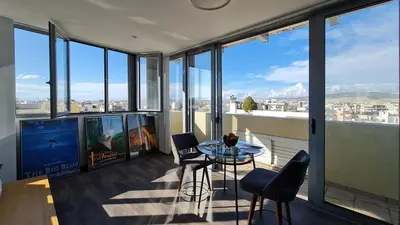 a balcony with a table and chairs in a room with windows at Xenophon Suite at National Opera SNFCC Park in Athens