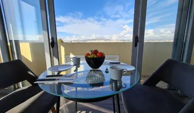 a glass table with a bowl of fruit on a balcony at Xenophon Suite at National Opera SNFCC Park in Athens