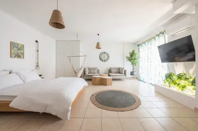 a white bedroom with a bed and a living room at Athenian home in Athens