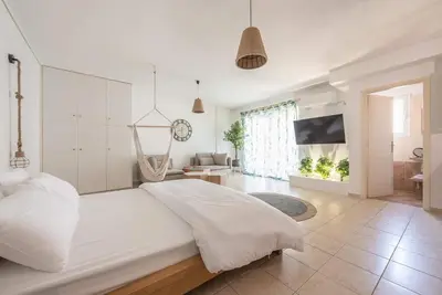 a white bedroom with a large bed and a swing at Athenian home in Athens