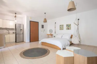 a white bedroom with a bed and a kitchen at Athenian home in Athens