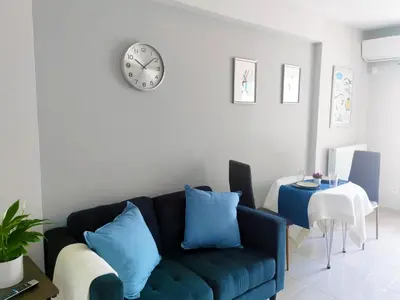 a living room with a blue couch and a clock on the wall at Santo House in Athens