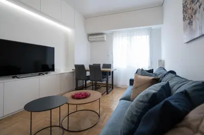 a living room with a blue couch and a flat screen tv at The Spiritual Athens Apartment in Athens
