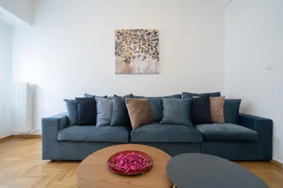 a blue couch in a living room with a table at The Spiritual Athens Apartment in Athens