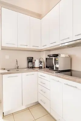 a white kitchen with white cabinets and a microwave at Modern full apt near acropolis/vaccinatedHosts in Athens