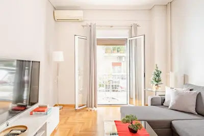 a living room with a couch and a large window at Modern full apt near acropolis/vaccinatedHosts in Athens