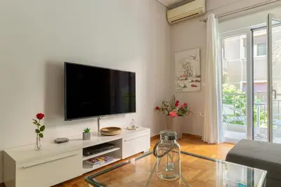 a living room with a flat screen tv on a white entertainment center at Modern full apt near acropolis/vaccinatedHosts in Athens