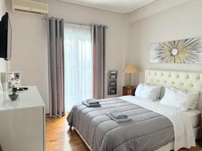 a white bedroom with a large bed and a window at Modern full apt near acropolis/vaccinatedHosts in Athens