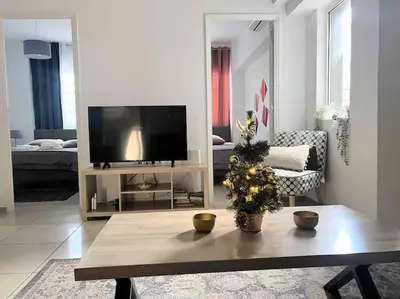 a living room with a television and a christmas tree on a table at Brand New Bright modern 6bdr apt-1min to Acropolis in Athens