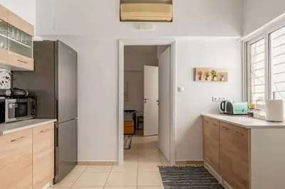 a kitchen with white walls and wooden cabinets at Brand New Bright modern 6bdr apt-1min to Acropolis in Athens
