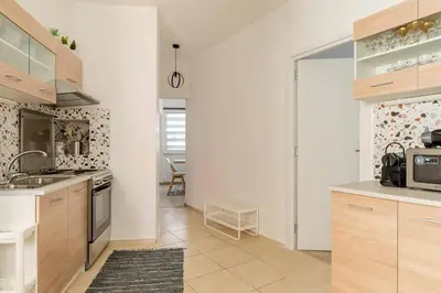 a kitchen with white walls and wooden cabinets at Brand New Bright modern 6bdr apt-1min to Acropolis in Athens