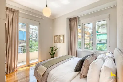 a bedroom with a large bed and windows at Contemporary 2-BDR APT near Kalimarmaro & Alsos Park! in Athens