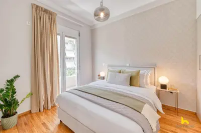a white bedroom with a large bed and a window at Contemporary 2-BDR APT near Kalimarmaro & Alsos Park! in Athens