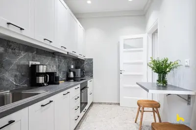 a kitchen with white cabinets and a counter and a stool at Contemporary 2-BDR APT near Kalimarmaro & Alsos Park! in Athens
