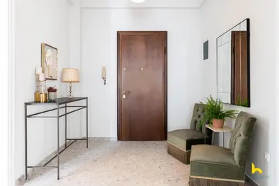 a living room with a wooden door and a chair at Contemporary 2-BDR APT near Kalimarmaro & Alsos Park! in Athens