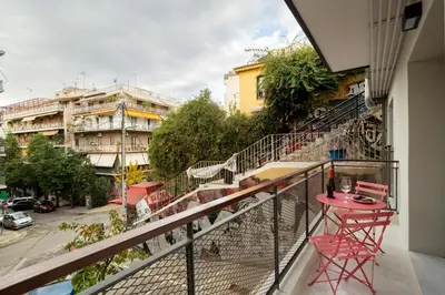 a balcony with a red table and chairs on a street at Strefi Hill Suites in Athens