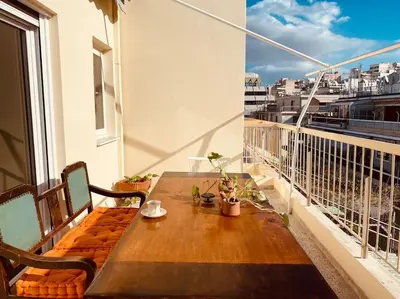 a wooden table and chairs on a balcony with a view at Athens Skylight Condo in Athens