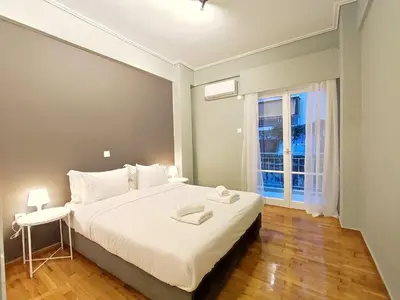 a bedroom with a large white bed and a window at Veno Apartments Goudi in Athens