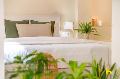 a bedroom with a white bed with green pillows and plants at Romantic Luxury Hideaway Near Acropolis with Jacuzzi in Athens