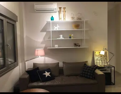 a living room with a couch and white shelves at Nikaia Metro House in Piraeus