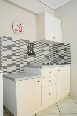 a kitchen with white cabinets and black and white tiles at The frescamento.collection apartment in Athens