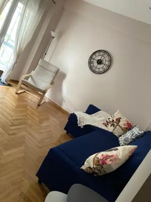 a living room with a chair and a clock on the wall at Bijou Kalamakiou (Athens Riviera) in Athens