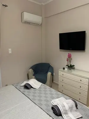 a bedroom with a bed and a tv and a chair at Bijou Kalamakiou (Athens Riviera) in Athens