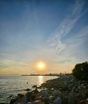 a sunset over the water with a rocky beach at Bijou Kalamakiou (Athens Riviera) in Athens
